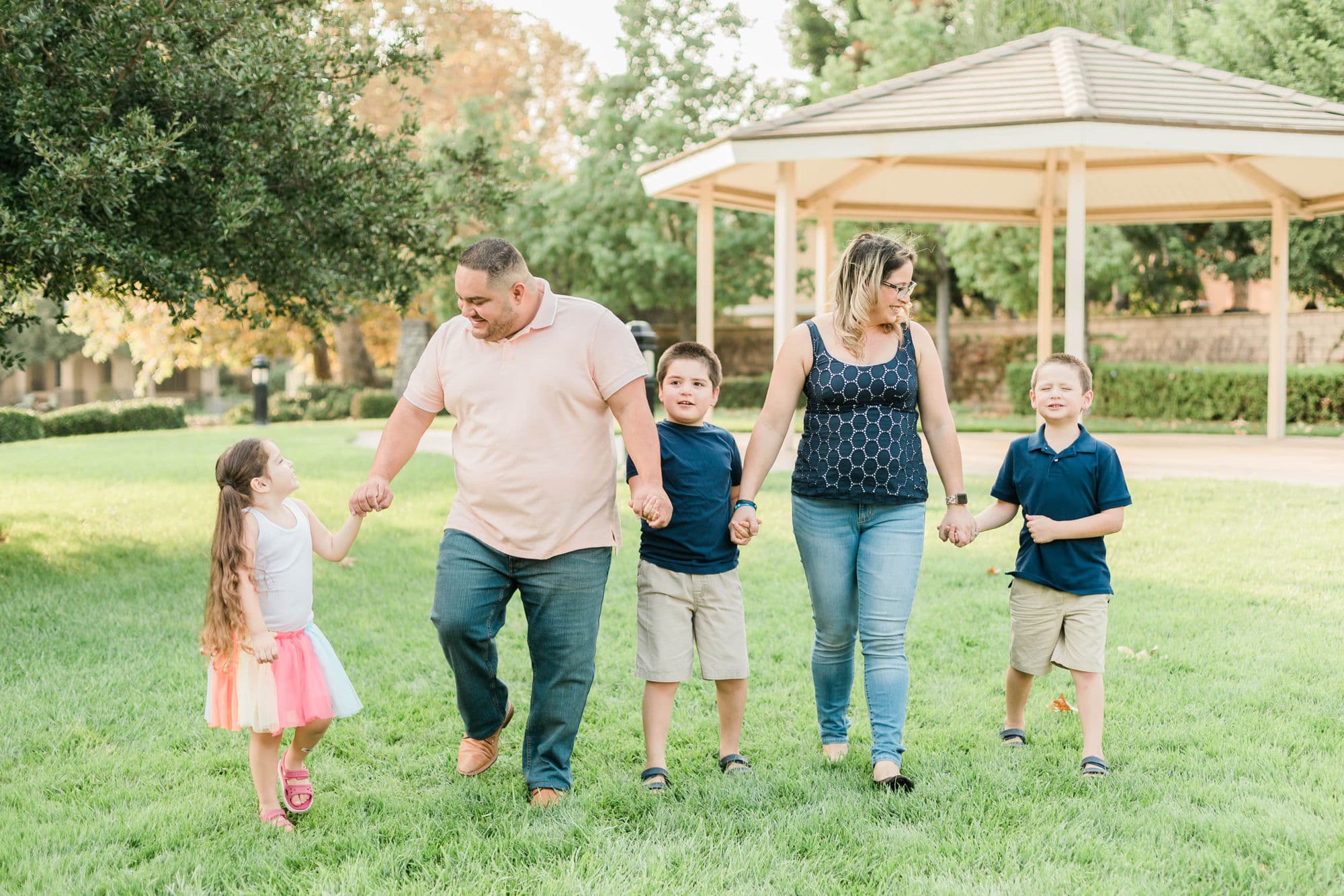 A family standing together outdoors, smiling in warm natural light.
